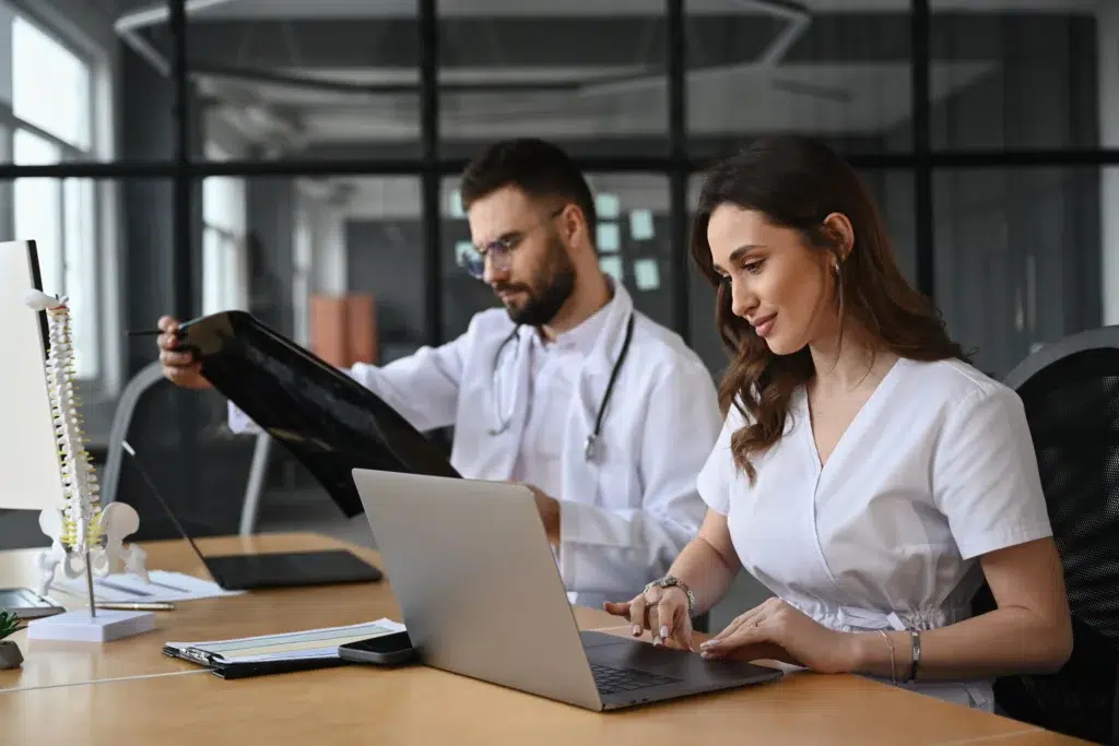 Two doctors in a medical office discussing a patient case before documenting the encounter with the pos 11 in medical billing code.