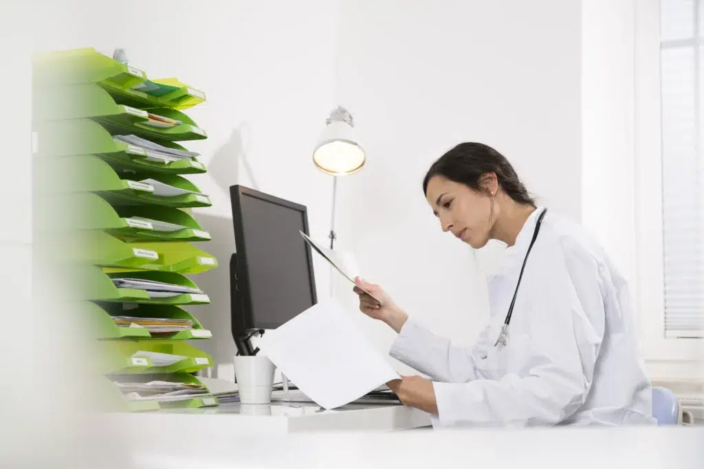 Female doctor at a desk reviewing clinical documentation to ensure the correct use of pos 11 in medical billing for office encounters.
