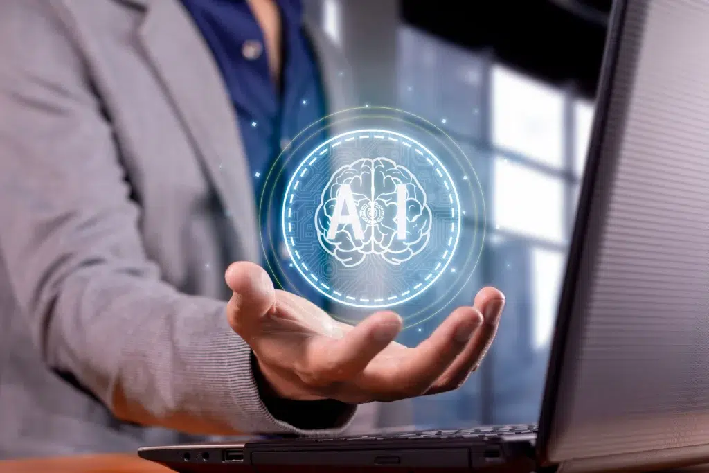 Close-up of a hand holding a glowing holographic brain with the 'AI' symbol, representing the core integration of artificial intelligence in revenue cycle management for predictive analytics.