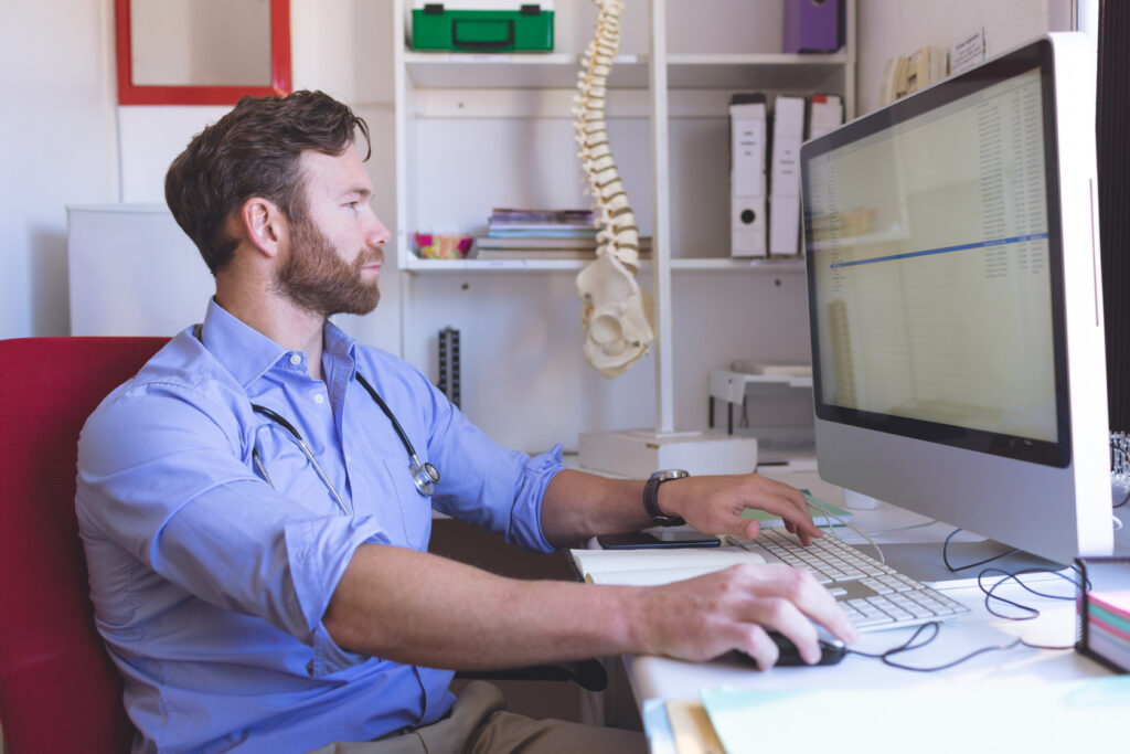Chiropractic billing services specialist reviewing a spinal manipulation claim at his desk